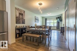 Dining area featuring wood-finish flooring, a contemporary chandelier, two panel doors, and an integrated shelving unit - 