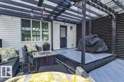 Deck featuring a dark-stained wood pergola, string lights, and light gray wood-finish decking - 