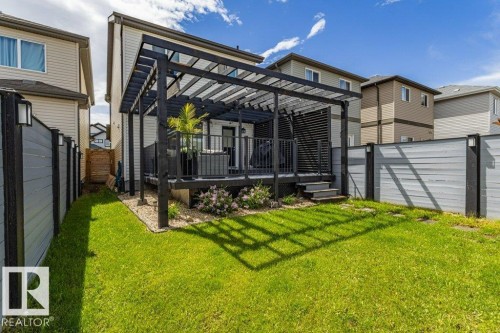 Expansive green lawn with a dark wood pergola covering a raised deck - 17123 49 Street, Edmonton, AB 