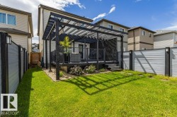 Expansive green lawn with a dark wood pergola covering a raised deck - 