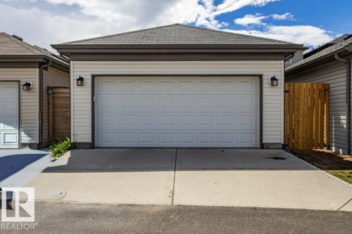Two-car garage featuring a paneled white door, white siding, and a dark shingled roof - 17123 49 Street, Edmonton, AB 