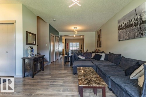 Open-concept living space featuring wood-finish flooring, a contemporary ceiling light fixture, and a built-in closet with bifold doors - 17123 49 Street, Edmonton, AB 