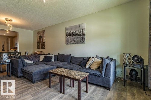 Spacious living area featuring wood-finish flooring, light-toned walls, and a contemporary ceiling light fixture - 17123 49 Street, Edmonton, AB 