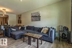 Spacious living area featuring wood-finish flooring, light-toned walls, and a contemporary ceiling light fixture - 