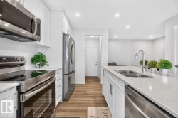 Modern kitchen featuring white shaker cabinetry, stainless steel appliances, a white geometric tile backsplash, wood-finish flooring, and a kitchen island with an undermount double sink - 
