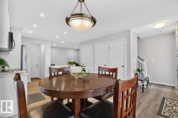 Dining area featuring a circular wood-finish table, overhead drum pendant light, and recessed lighting - 