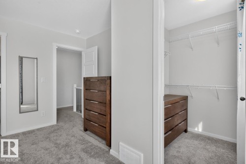 Walk-in closet with wire shelving system and dark wood-finish built-in storage - 1022 Hearthstone Boulevard, Sherwood Park, AB 