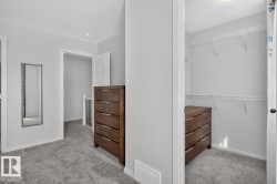 Walk-in closet with wire shelving system and dark wood-finish built-in storage - 