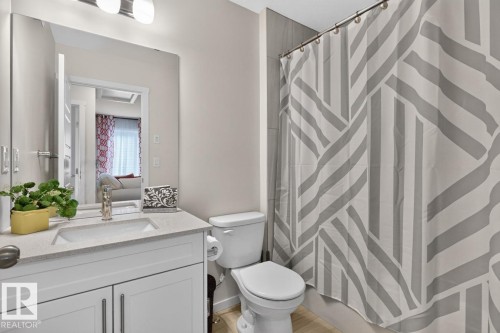 Bathroom featuring a white vanity with brushed nickel hardware, an integrated sink, and a speckled countertop - 1022 Hearthstone Boulevard, Sherwood Park, AB 