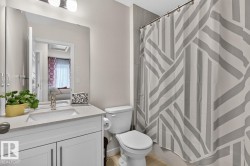 Bathroom featuring a white vanity with brushed nickel hardware, an integrated sink, and a speckled countertop - 