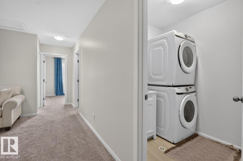 Dedicated laundry area featuring stacked front-load appliances and wood-finish flooring - 1022 Hearthstone Boulevard, Sherwood Park, AB 