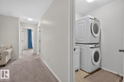 Dedicated laundry area featuring stacked front-load appliances and wood-finish flooring - 