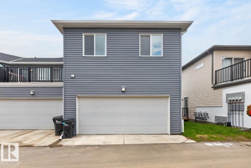 Gray horizontal siding facade with white trim, featuring a single-car garage and two upper-level windows - 1022 Hearthstone Boulevard, Sherwood Park, AB 