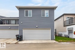 Gray horizontal siding facade with white trim, featuring a single-car garage and two upper-level windows - 