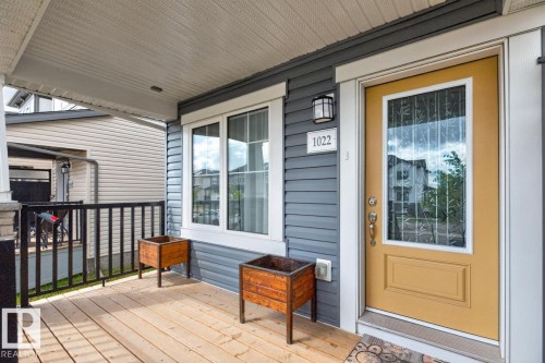 Covered front porch with wood-finish decking, dark gray siding, and white trim - 1022 Hearthstone Boulevard, Sherwood Park, AB 