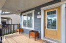 Covered front porch with wood-finish decking, dark gray siding, and white trim - 1022 Hearthstone Boulevard, Sherwood Park, AB 