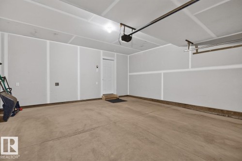 Spacious garage featuring a concrete floor, painted walls, overhead lighting, an automatic garage door opener, and a built-in storage rack - 1022 Hearthstone Boulevard, Sherwood Park, AB 