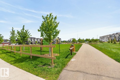 Expansive green space featuring a paved walking path, mature trees, and a split-rail fence - 1022 Hearthstone Boulevard, Sherwood Park, AB 