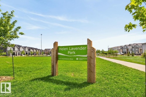 Green space featuring a park sign, a paved walking path, and a backdrop of contemporary residential architecture - 1022 Hearthstone Boulevard, Sherwood Park, AB 