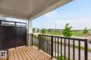 Front porch featuring wood-finish decking, black metal railings, and a privacy screen - 1022 Hearthstone Boulevard, Sherwood Park, AB 