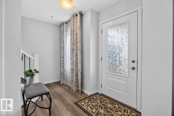 Entryway featuring a white paneled door with decorative frosted glass, overhead flush-mount lighting, and wood-finish flooring - 