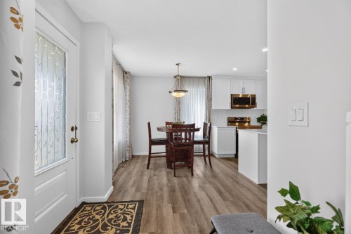 Foyer featuring a white entry door with frosted glass panel, wood-finish flooring, and light gray wall paint - 1022 Hearthstone Boulevard, Sherwood Park, AB 