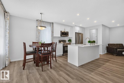 Open-concept living space featuring wood-finish flooring, recessed lighting, and a white kitchen island with an integrated sink - 1022 Hearthstone Boulevard, Sherwood Park, AB 
