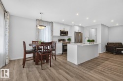 Open-concept living space featuring wood-finish flooring, recessed lighting, and a white kitchen island with an integrated sink - 
