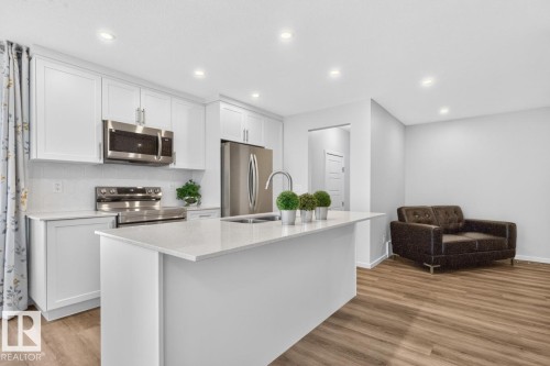 Contemporary kitchen featuring white cabinetry, stainless steel appliances, a center island with a sink, and recessed lighting - 1022 Hearthstone Boulevard, Sherwood Park, AB 
