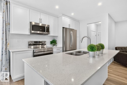 Kitchen island with a double basin stainless steel sink and gooseneck faucet - 1022 Hearthstone Boulevard, Sherwood Park, AB 