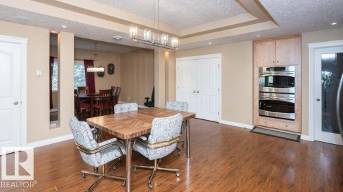 Spacious dining area featuring wood-finish flooring, a tray ceiling, and a contemporary chandelier - 58505 Rng Rd 260, Rural Westlock County, AB 