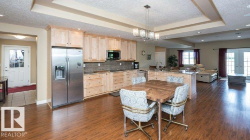 Expansive kitchen featuring wood-finish flooring, light wood cabinetry, stainless steel appliances, and a central island with a sink - 58505 Rng Rd 260, Rural Westlock County, AB 