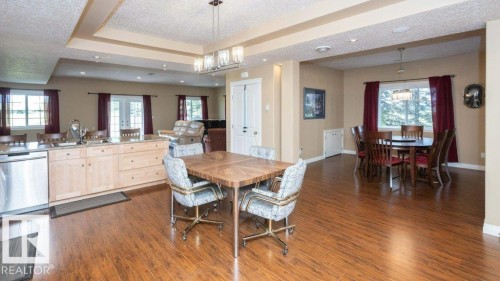 Expansive open-concept room featuring wood-finish flooring, a kitchen island with light wood cabinetry and a light-toned countertop, and multiple windows - 58505 Rng Rd 260, Rural Westlock County, AB 
