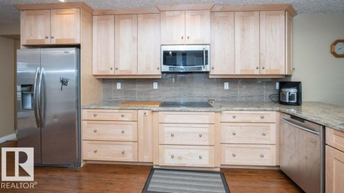 Kitchen featuring light wood cabinetry, stainless steel appliances, granite countertops, and a tiled backsplash - 58505 Rng Rd 260, Rural Westlock County, AB 