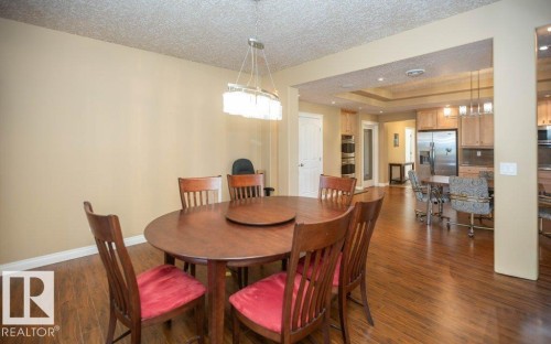 Open concept dining area featuring wood-finish flooring, a modern linear chandelier, and an expansive doorway opening to the kitchen - 58505 Rng Rd 260, Rural Westlock County, AB 