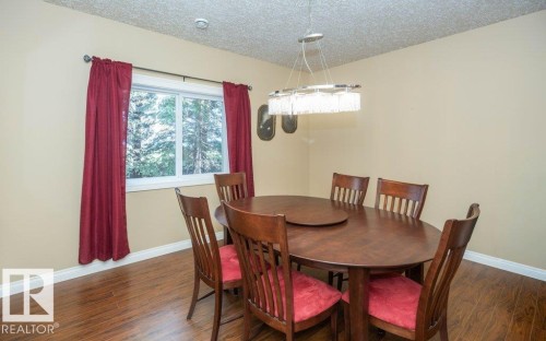 Dining area featuring wood-finish flooring, a contemporary linear chandelier, and a large window - 58505 Rng Rd 260, Rural Westlock County, AB 