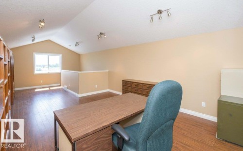 Spacious loft area featuring vaulted ceilings, wood-finish flooring, a generous window, and track lighting fixtures - 58505 Rng Rd 260, Rural Westlock County, AB 