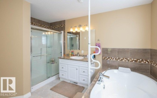 Bathroom featuring a white vanity with a granite-style countertop, a framed mirror, and a four-bulb vanity light fixture - 58505 Rng Rd 260, Rural Westlock County, AB 