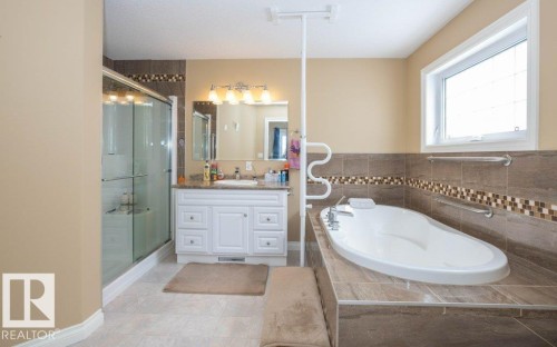 Bathroom featuring a built-in soaking tub, tiled surround, and integrated grab bars - 58505 Rng Rd 260, Rural Westlock County, AB 