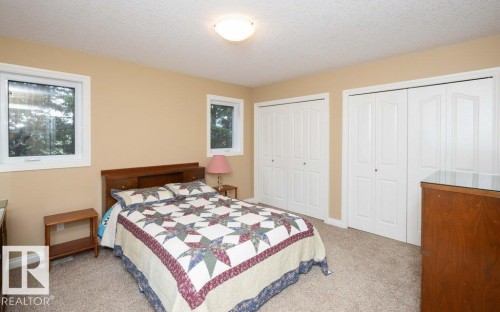Carpeted room featuring two bifold door closets, two white-framed windows, and a flush mount ceiling light - 58505 Rng Rd 260, Rural Westlock County, AB 