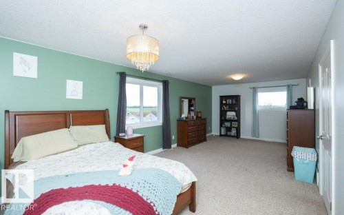 Spacious bedroom featuring neutral carpeting and a decorative chandelier - 58505 Rng Rd 260, Rural Westlock County, AB 
