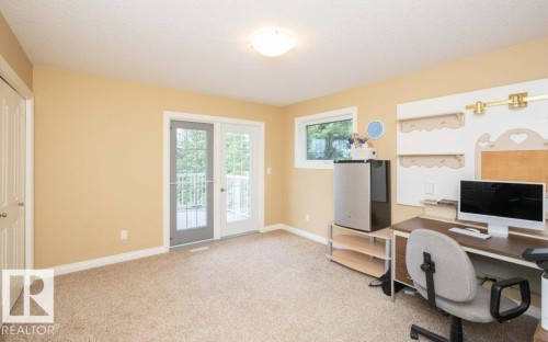 Carpeted interior space with neutral walls, featuring double French doors leading to an exterior balcony - 58505 Rng Rd 260, Rural Westlock County, AB 