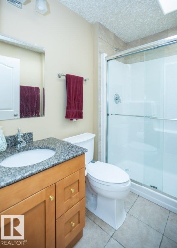 Bathroom featuring a wood-finish vanity with a granite countertop and an undermount sink - 58505 Rng Rd 260, Rural Westlock County, AB 