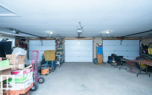 Spacious garage featuring three white sectional doors, concrete flooring, and overhead lighting - 58505 Rng Rd 260, Rural Westlock County, AB 