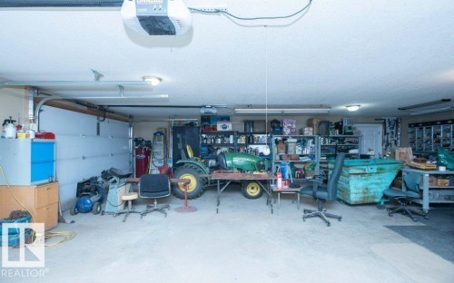 Spacious garage featuring a concrete floor, multiple overhead light fixtures, and an automatic garage door opener - 58505 Rng Rd 260, Rural Westlock County, AB 