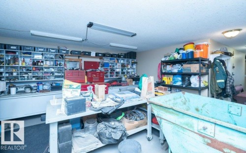 Dedicated workshop space featuring extensive built-in shelving, durable work surfaces, and overhead fluorescent lighting - 58505 Rng Rd 260, Rural Westlock County, AB 