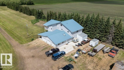 Modern residence featuring a light gray exterior with a blue metal roof, an attached three-car garage, and a second-story balcony - 58505 Rng Rd 260, Rural Westlock County, AB 