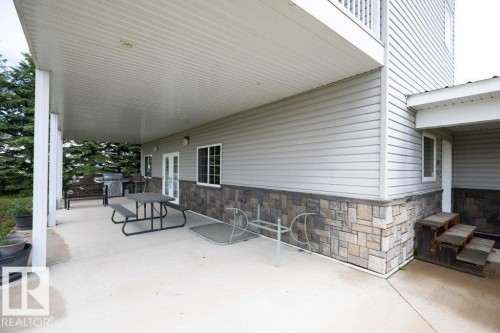 Concrete patio featuring a covered area with a paneled ceiling, supported by white columns - 58505 Rng Rd 260, Rural Westlock County, AB 