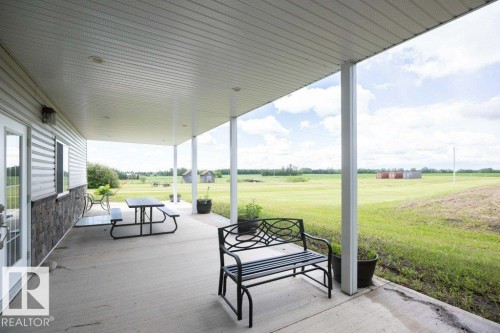 Expansive covered concrete patio featuring a white vinyl siding exterior with stone veneer accents - 58505 Rng Rd 260, Rural Westlock County, AB 