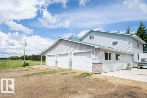 Three-car garage with white panel doors and stone veneer accents - 58505 Rng Rd 260, Rural Westlock County, AB 